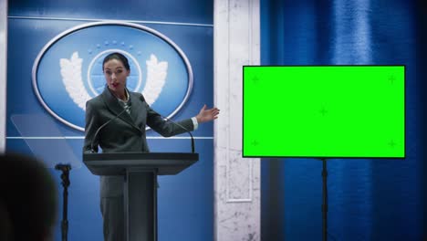 organization female representative speaking at press conference in government building with green screen mock up on display. press officer delivering a speech at summit. minister in congress.