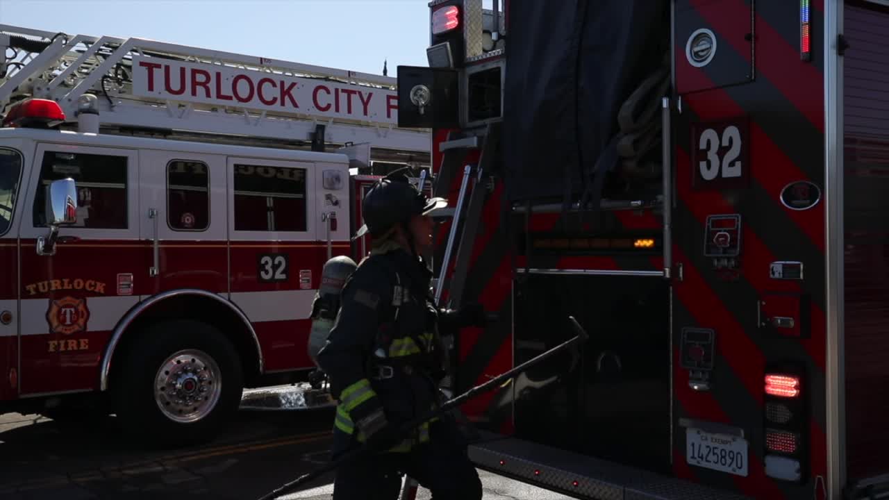 slow motion 60 fps firefighters pulling out equipment from fire trucks in turlock california cali dressed fully with jackets helmets hustling with teamwork epic cinematic midday sunny