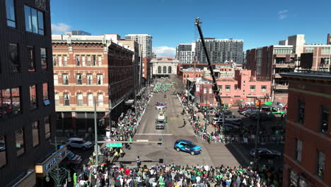 aerial view of crowds surrounding saint patrick's day floats driving through downtown denver