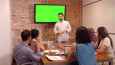 businessman standing by screen to deliver presentation