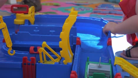 view of child playing with water toy set with small plastic boats floating past