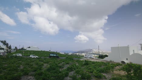 Panorama-of-cars-driving-atop-island-hill-in-Santorini,-Greece