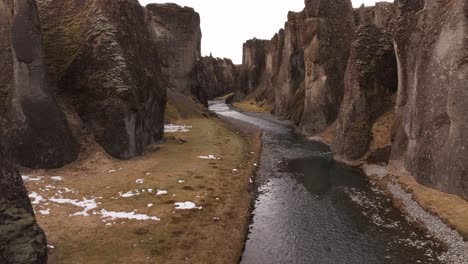 southern iceland’s fjaðrárgljúfur canyon - drone gliding through towering cliffs, winding river and mossy terrain.