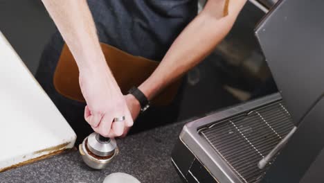 barista caucásico con delantal preparando café para la máquina de café en una cafetería