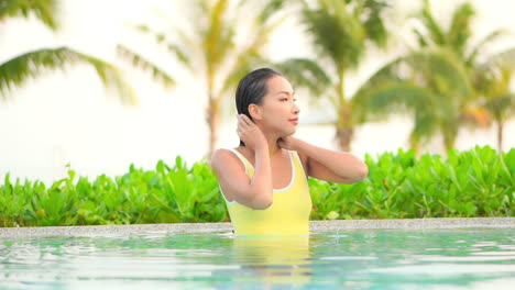 Zierliche-Asiatische-Frau,-Die-An-Heißen-Sommertagen-Ihr-Nasses-Haar-In-Einem-Schwimmbad-Streichelt