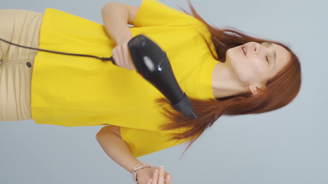 Video vertical de mujer cantando y bailando con secador de pelo