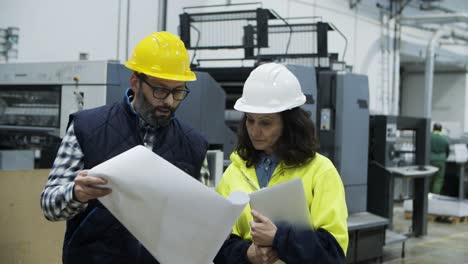 Front-view-of-printing-employees-inspecting-plan-of-building