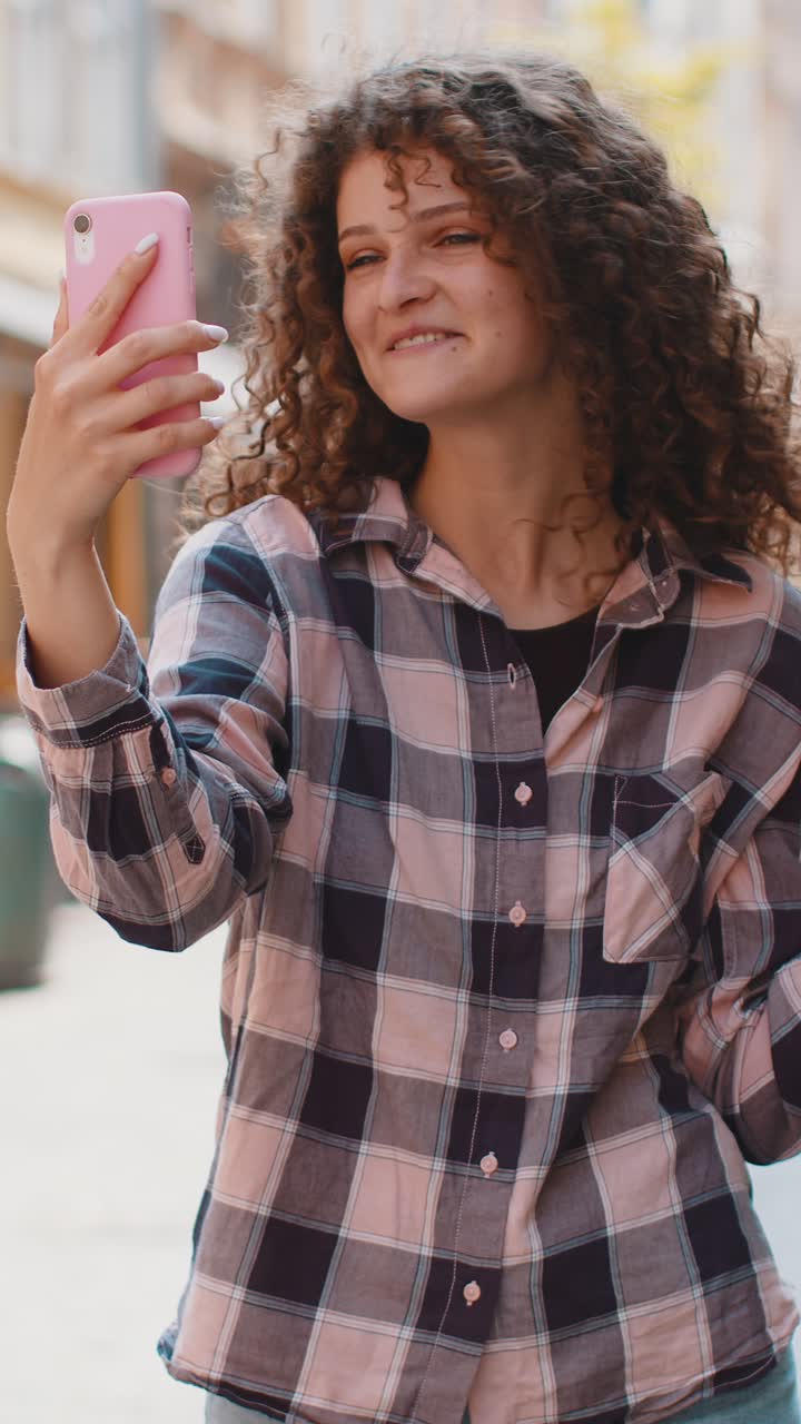 Giovane blogger che si fa un selfie con lo smartphone e fa una videoconferenza online con gli abbonati in una strada della città