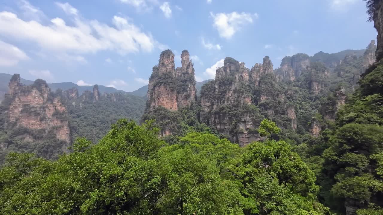 Wide pan right showing the iconic forested sandstone towers of Zhangjiajie under a clear sky