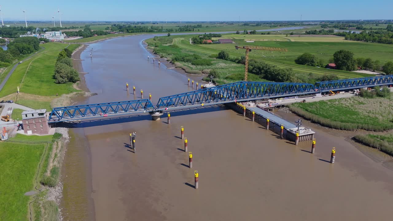 Wide aerial view of the Friesenbrücke across the Ems River in Northern Germany. The modern lift-swing railway bridge appears closed, showing its structural length and construction details.