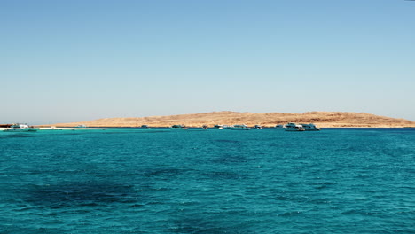 Flying-Above-Blue-Waters-Of-Red-Sea-With-View-Of-Hurghada-Coastline-Against-Blue-Sky-In-Distance