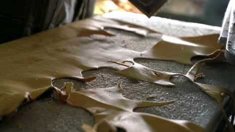 worker cutting leather gloves on press, manufacturing process on industrial press