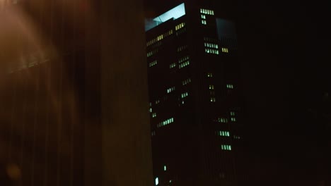 vista nocturna de un edificio de oficinas iluminado desde un coche en movimiento, capturando la esencia de la vida urbana después de la oscuridad