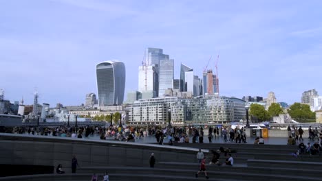 people walking with view of city of london skyscrapers and modern office buildings on a sunny day with clear skies