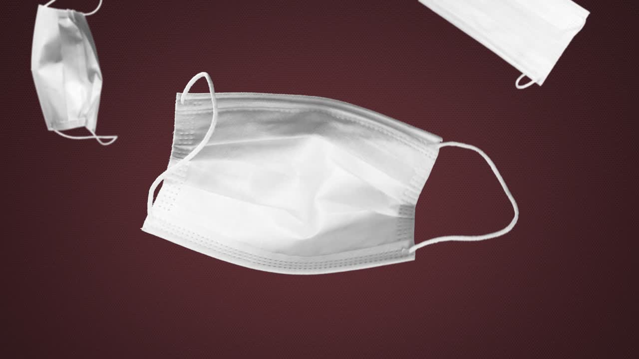 공중에서 떠다니며 어두운 빨간색 배경에 얼굴 마스크를 떨어뜨립니다.