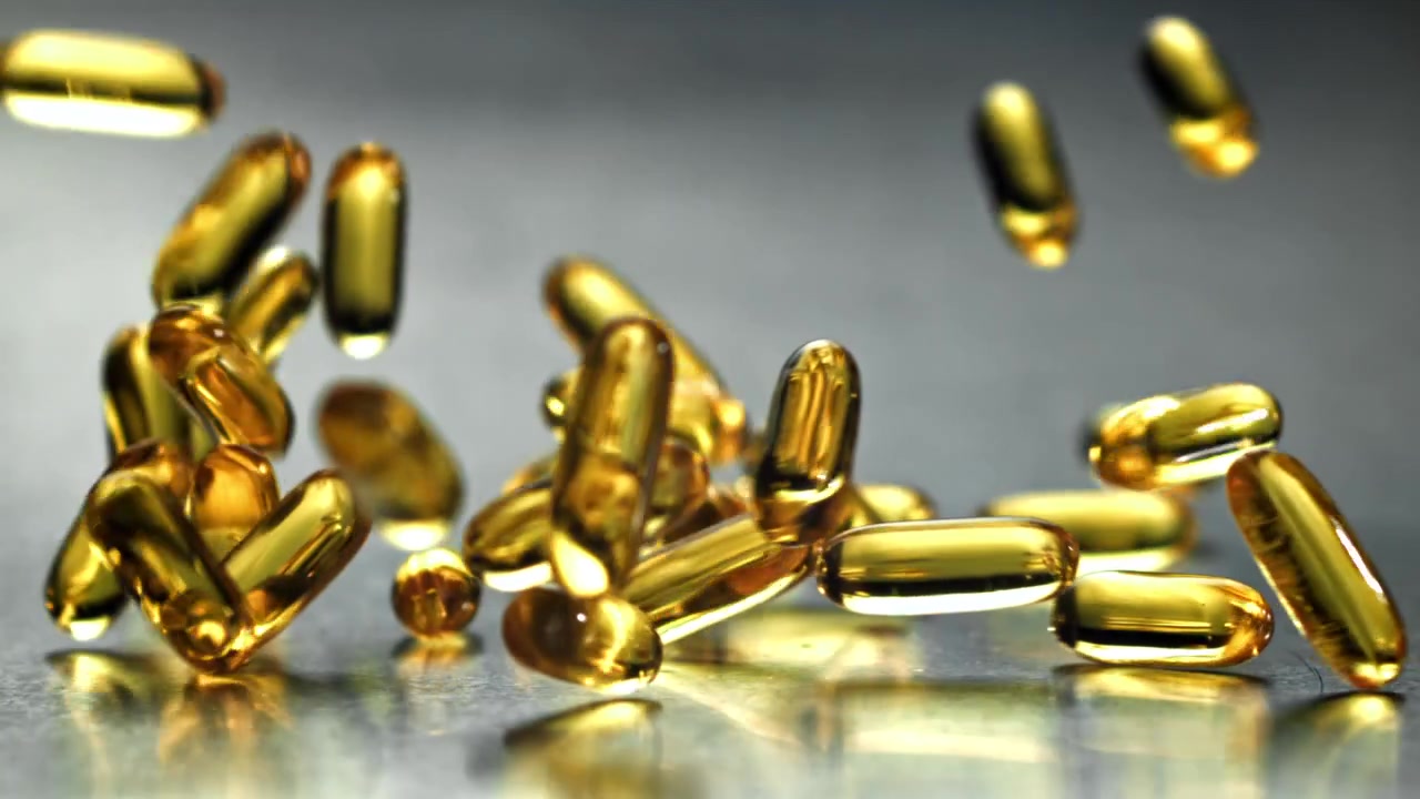 Capsule softgel dorate che cadono al rallentatore