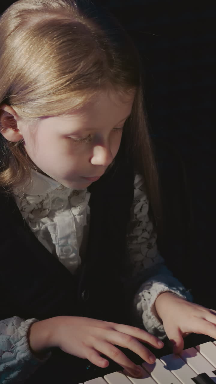 유치원 아동은 전기 키보드에서 멜로디를 연주합니다. 은 머리 작은 소녀는 녹음 스튜디오에서 음악 작곡을 연주합니다. 음향 어린이 공연