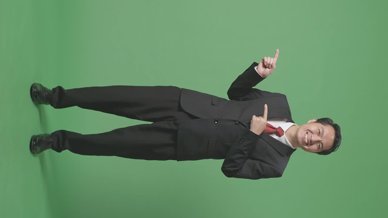 녹색 스크린에 서 있는 동안 을 가리키는 미소를 가진 아시아 사업가의 몸이 가득 차 있습니다.