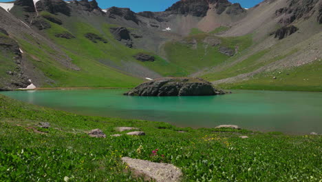 Dreamy-heavenly-Island-Lake-Silverton-Ice-Lake-Basin-aerial-drone-cinematic-unreal-Caribbean-aqua-blue-Silverton-Colorado-lush-green-wildflower-summer-snow-melting-Rocky-Mountains-forward-reveal-up