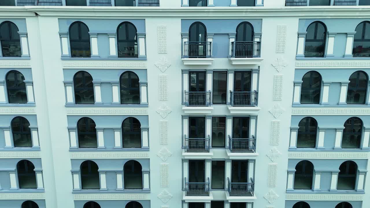 Drone shot of Grand World development on Phu Quoc Island, Vietnam, showcasing a replica of Venice-style architecture in a quiet, empty residential area surrounded by lush greenery.