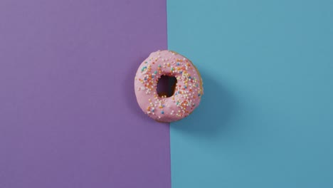 video de una rosquilla con glaseado sobre fondo púrpura y azul