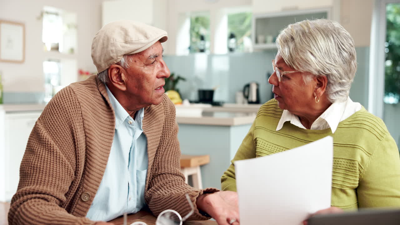 una pareja de ancianos discutiendo documentos financieros en casa