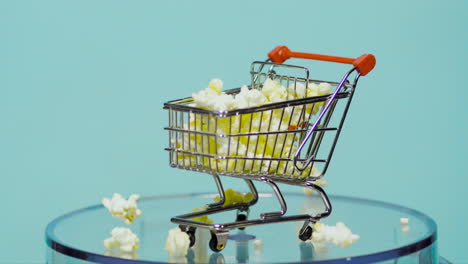 shopping kart filled with popcorn in slow motion with baby blue background