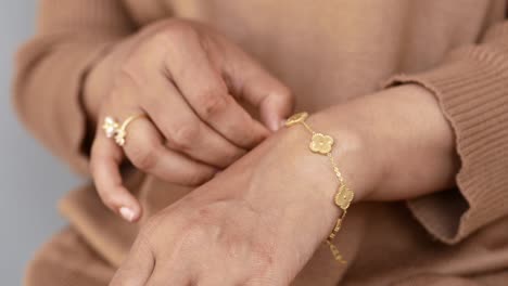 primer plano de la mano de una mujer con una pulsera y un anillo de oro