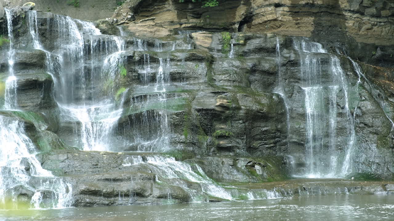 una cascada de agua en una selva tropical con roca