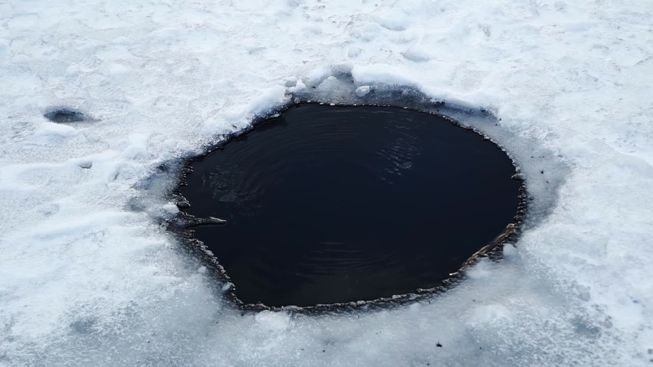 un pequeño agujero con burbujas que suben a la superficie en el lago congelado del embalse de tibble fork para pescar en hielo en american fork canyon, ut