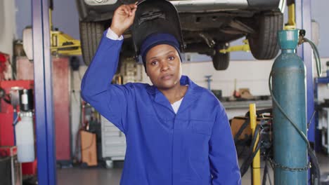 Video-of-african-american-female-car-mechanic,-taking-off-welding-mask