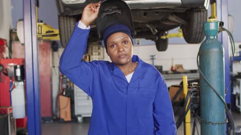video of african american female car mechanic, taking off welding mask