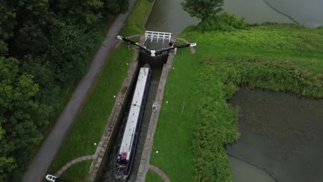 69ft-canal-boat-going-through-a-large-wooden-lock,-the-location-is-the-famous-Kennet-and-Avon-canal-and-the-video-was-shot-on-my-dji-drone