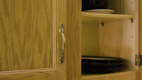 man pulls plate out of cupboard side angle