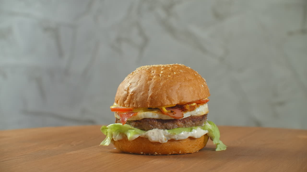 una hamburguesa grande y sabrosa con carne, cebollas, verduras, queso derretido y lechuga.