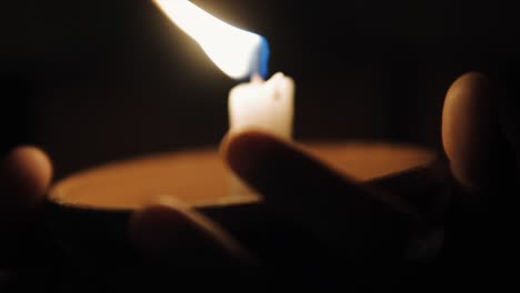 woman's hands holding a single candle in a clay pot that blurs with camera movement