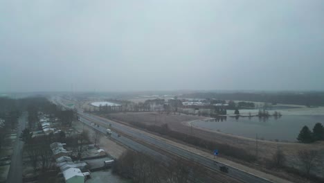 Flying-Over-Main-Road-Near-Beautiful-Lake-In-Snowy-Weather-In-Warren,-Ohio,-USA