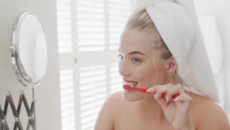 Happy-caucasian-plus-size-woman-in-front-of-mirror-with-towel-on-head-brushing-teeth-in-slow-motion