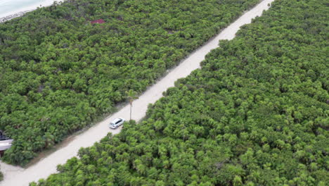 suv driving on a peninsula traveling through green tulum mexico side profile shot