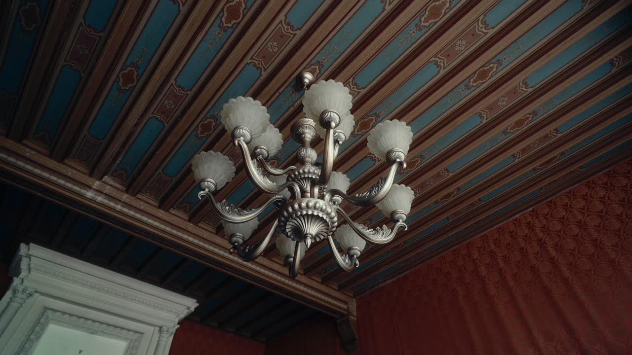 Ornate Chandelier Hanging from a Decorated Ceiling in a Historic Room
