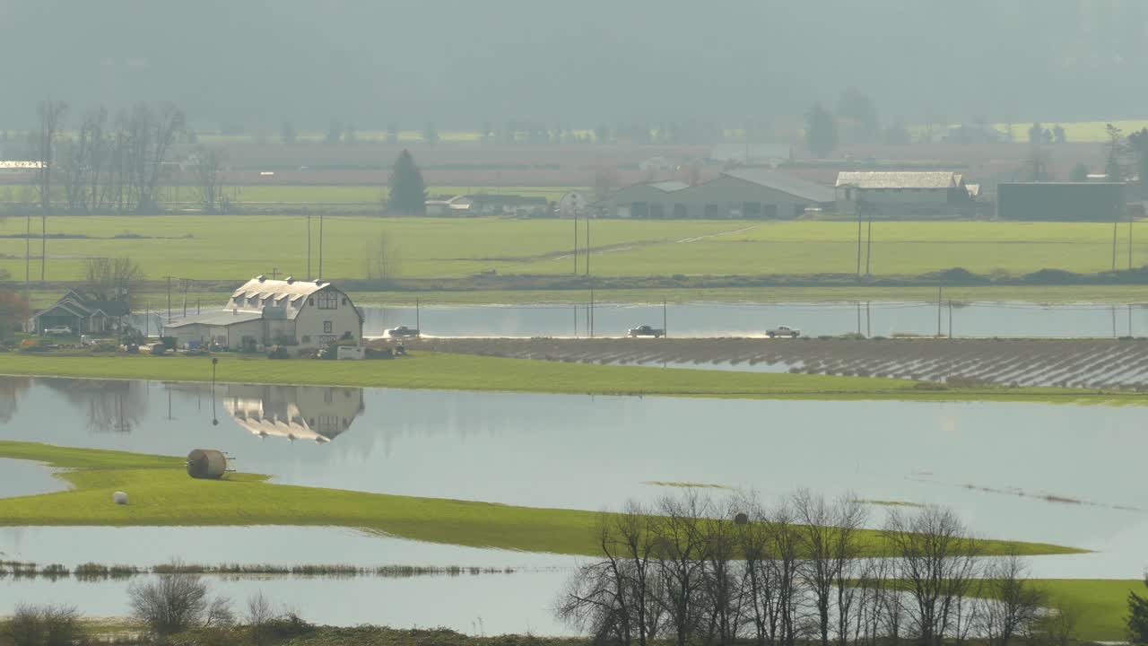 движение по мокрой дороге с фермерским домом и окружающими полями, затопленными в результате сильного дождя, британская колумбия, канада