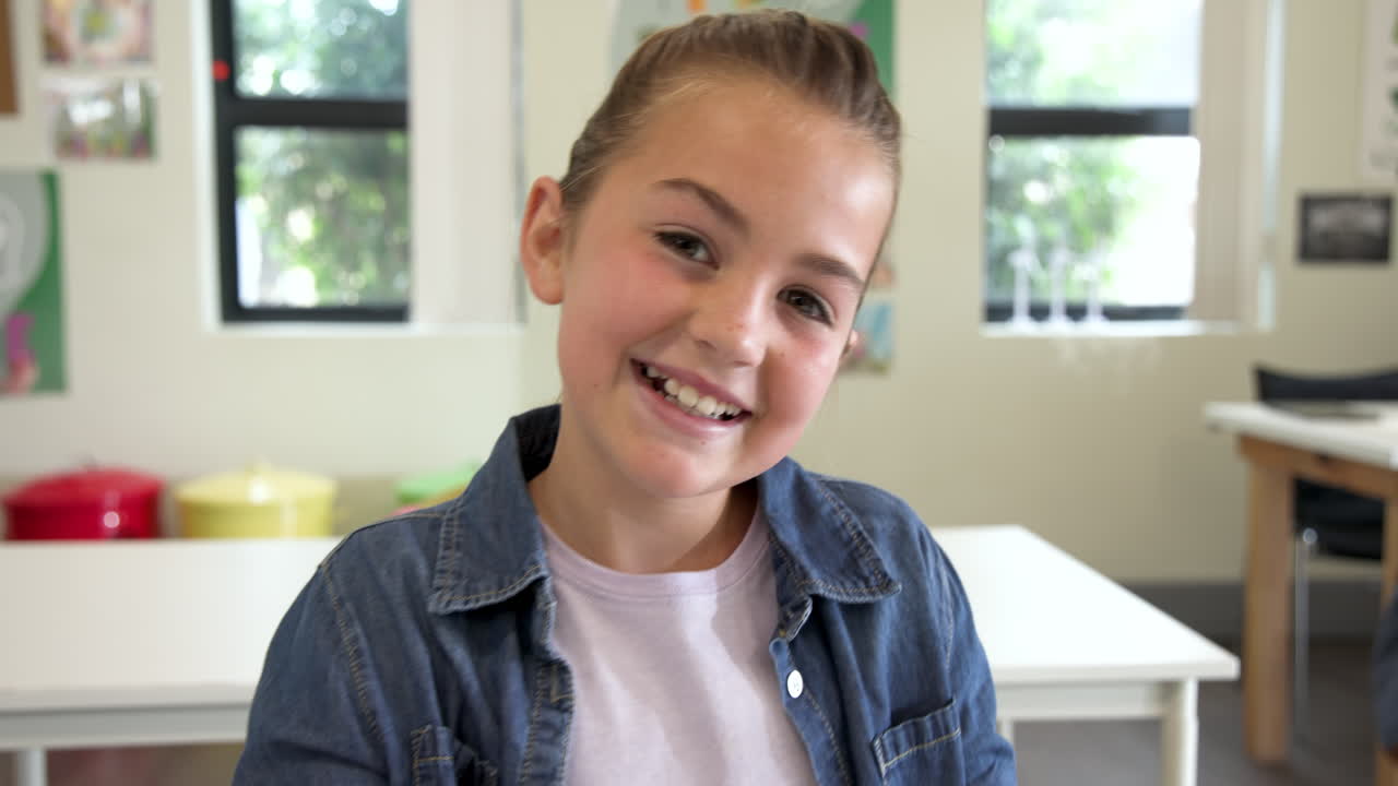Smiling girl in classroom wearing denim jacket, enjoying school day