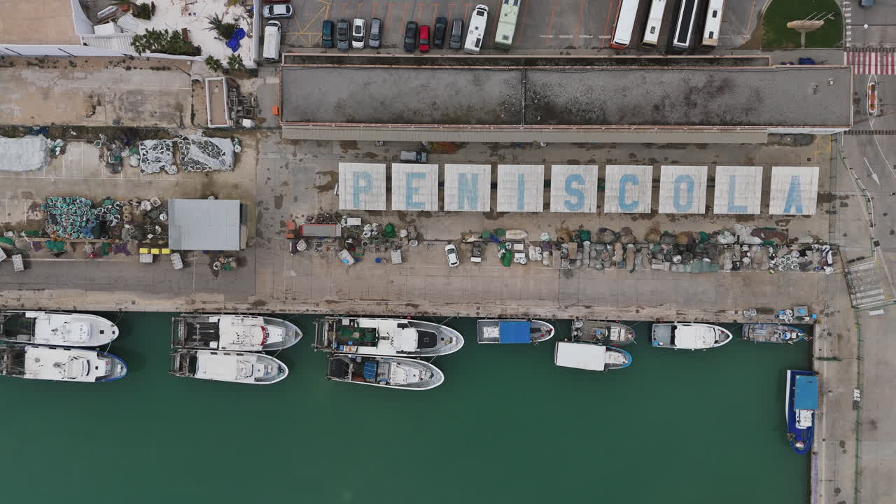 Close drone shot over Puerto de Peniscola marina with docked boats in calm green water