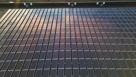 car on street in industrial area with modern factory and large solar panels om rooftop. aerial backwards shot. reflection on units.