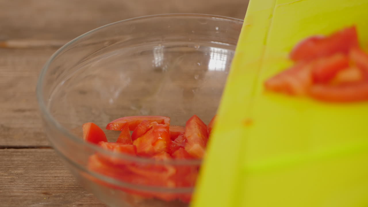 갓 자른 토마토 조각을 도마에서 그릇에 넣습니다.