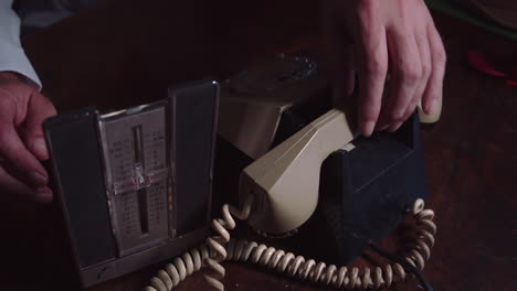 the person looks up a phone number in the organizer and then dials it on the vintage rotary dial phone