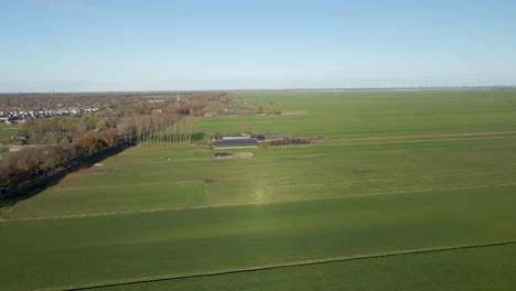 antenne van een boerderij in de verte omringd door groene weiden op het platteland van nederland