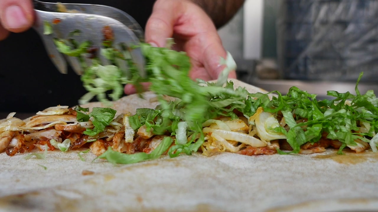 Chef Adding Fresh Lettuce to a Kebab Wrap