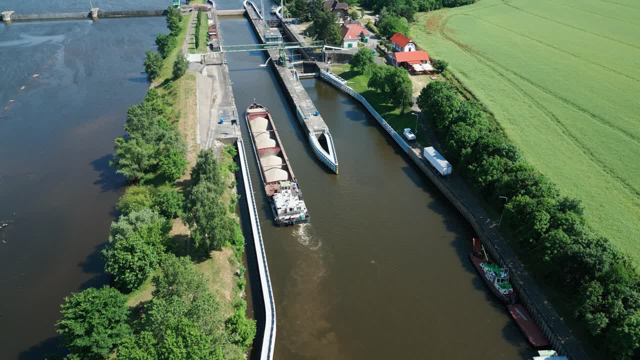 드론 카메라가 강 잠금장에 항해하는 모래 화물 보트를 추적합니다.