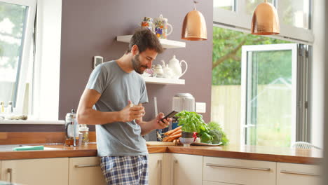 hombre usando el teléfono mientras toma café en la cocina de la mañana